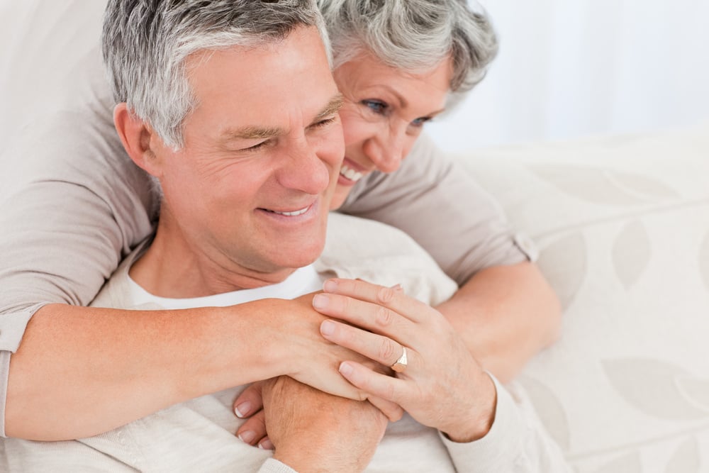 Mature woman hugging her husband at home