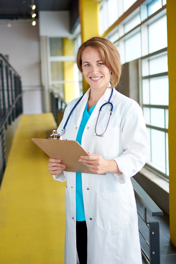 Portrait of a female doctor holding her patient chart in bright modern hospital